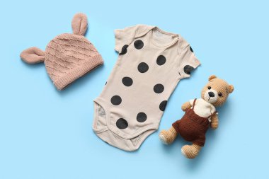 Mavi arka planda oyuncak ayı ve şapkalı bebek kıyafeti