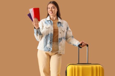 Bej arka planda bileti ve bavulu olan bir kadın turist çantası.