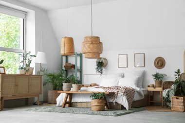 Yatak, bank ve ev bitkileri yatak odasının içindeki sepetlerde.