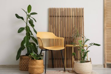 Sandalye, katlanan ekran ve odanın içindeki beyaz duvarın yanındaki çiçekli hasır sepetler.