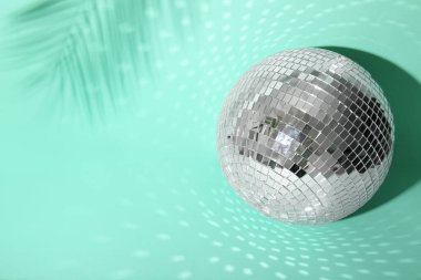 Turkuaz arka planda palmiye yaprağı gölgesi olan disko topu