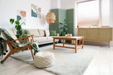 Yeşil katlanır ekran, kanepe, masa ve çekmeceler oturma odasının iç tarafında.