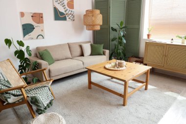 Bej kanepe, masa ve katlanan ekran, oturma odasının içinde.