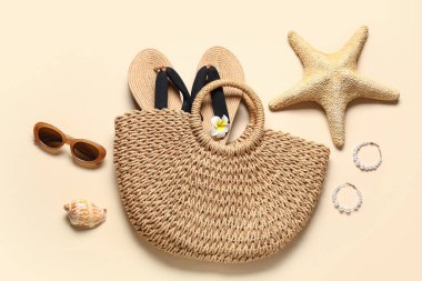 Terlikli plaj çantası, bej arka planda deniz yıldızı ve güneş gözlüğü.