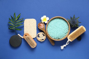 Güzel bir spa kompozisyonu, banyo malzemeleri, çiçekler ve mavi arka planda bir kase deniz tuzu.