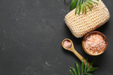 Yeşil yapraklı kompozisyon, banyo süngeri ve siyah grunge arka planında deniz tuzu olan kase.