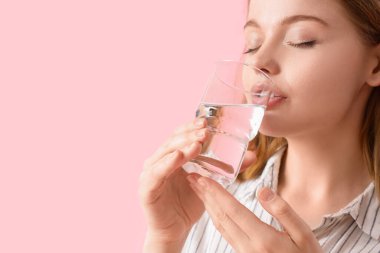 Pembe arka planda tatlı su içen genç bayan, yakın plan.