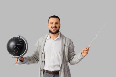 Işık arkaplanı üzerinde küresi ve işaretçisi olan erkek coğrafya öğretmeni
