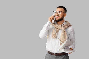 Erkek öğretmen açık arkaplanda telefonla konuşuyor.