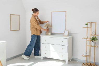 Evde klozette ampulü lambaya vidalayan genç kadın.