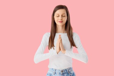 Pembe arka plan üzerinde meditasyon yapan genç bir kadın.