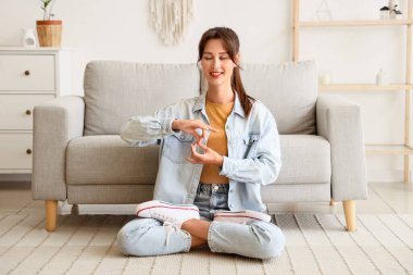 Evde halıda meditasyon yapan genç bir kadın.