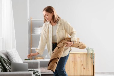 Evdeki kanepede sarılmış hasır halı ve dizüstü bilgisayarı olan genç bir kadın.