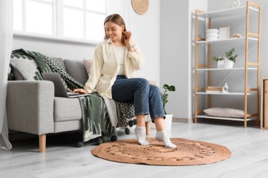 Kanepede dizüstü bilgisayar kullanan genç bir kadın.