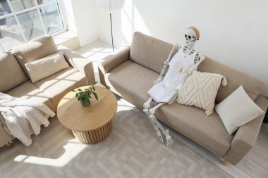 Oturma odasındaki kanepede kadın gibi giyinmiş insan iskeleti mankeni.