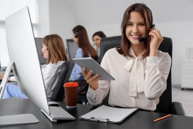 Ofiste tablet bilgisayarla çalışan kadın teknik destek ajanı