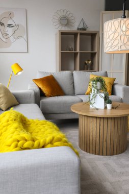 Işıl ışıl oturma odası, rahat gri kanepe, sehpa ve parlayan lambalar.