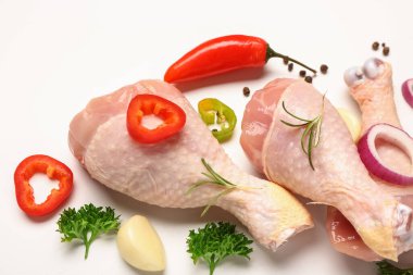 Beyaz arka planda çiğ tavuk bacağı ve baharatlı kompozisyon, yakın plan.