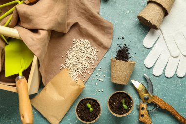 Bahçe aletleri, granüler gübre ve mavi grunge arkaplan üzerinde turba kapları bileşimi