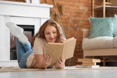 Evde kitap okuyan genç bir kadın.