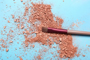 Mavi arka planda makyaj fırçası ve dağınık fosforlu kalem