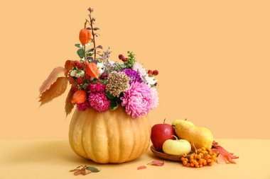 Balkabağı ve tabakta güzel bir sonbahar buketi ve turuncu arka planda taze meyveler.