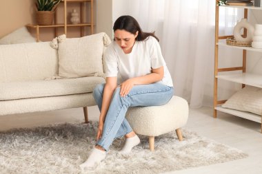 Genç bir kadın evdeki puf bacağında ağrıdan muzdarip.