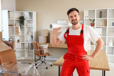 Ofisinde streç film rulosu olan erkek işçi.