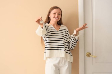 Anahtarları yeni evinin kapısını gösteren güzel genç bir kadın.