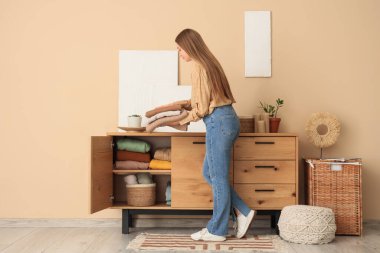 Güzel genç bir kadın evdeki dolabına temiz giysiler koyuyor.