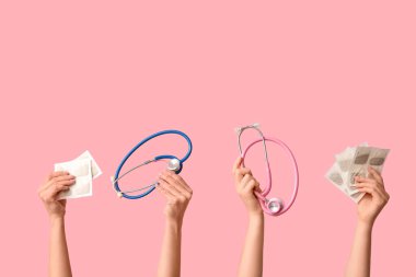 Hardal sıva ve pembe arka planda steteskoplu kadın elleri.