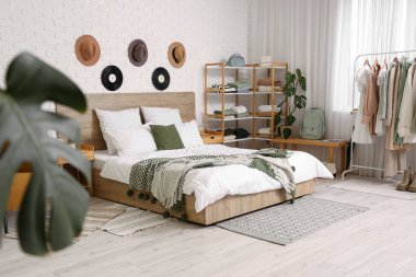 Rahat bir yatak, raflar ve yatak odasının iç kısımlarında giysi.