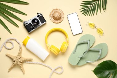 Kamera, kulaklık ve bej arka planda plaj aksesuarları olan cep telefonu.