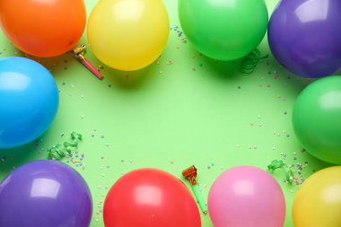 Parti ıslıkları ve yeşil arka planda konfetileri olan hava balonlarından yapılmış çerçeve