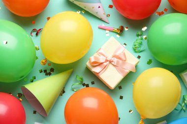 Hediyeli balonlar, parti şapkaları ve turkuaz arka planda konfeti.