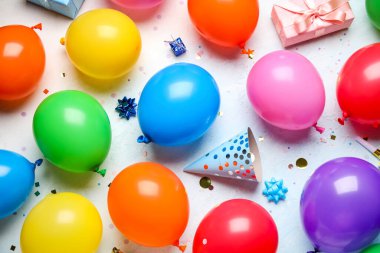 Hediyeli balonlar, açık mavi arka planda parti şapkası ve konfeti.