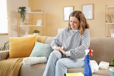 Temizlik yaparken kendini kaşıyan genç bir kadın. Alerji konsepti