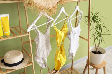 Odada yeşil duvarın yanında mayo ve palmiye ağaçları var.