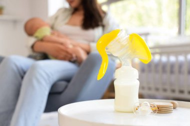 Göğüs pompası ve emzik masada anne ve bebeği yatak odasında, yakın plan.