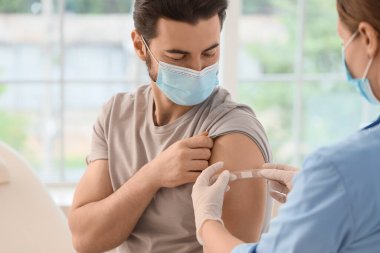 Klinikte aşıdan sonra doktor yaması uygulayan genç bir adam.