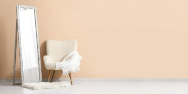 Odanın içindeki bej duvarın yanında yer aynası ve koltuk var. Tasarım için pankart