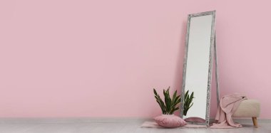 Zemin aynası, çiçek ve pouf pembe duvarın yanında.