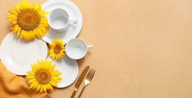 Altın çatal bıçak takımları ve kahverengi arka planda ayçiçekleri olan güzel bir masa.