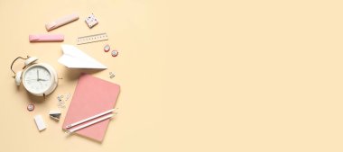 Alarm saati, kağıt uçak ve bej arkaplan üzerine farklı okul sayfası.