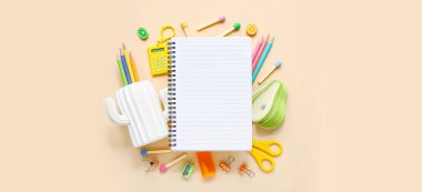 Bej arkaplanda farklı kırtasiye malzemesi olan defter