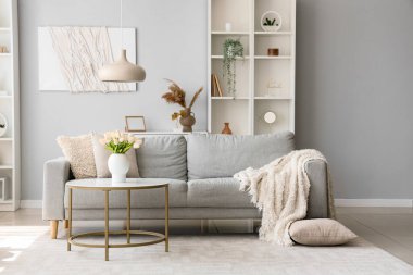 Yumuşak battaniyeli rahat gri kanepe ve oturma odasının iç tarafında kahve masası.