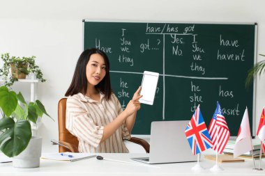 Sınıfta dil bilgisi dersi veren tablet bilgisayarlı kadın İngilizce öğretmeni.