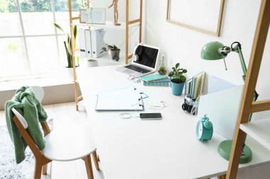 Ofisinde dizüstü bilgisayarı ve kırtasiyesi olan modern işyeri