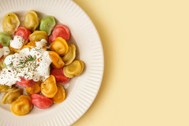 Ekşi kremalı ve dereotlu kaynamış renkli hamur tatlısı tabağı.