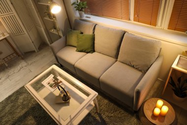 Gri kanepeli, yanan mumlu ve parlayan lambasıyla modern oturma odasının içinde.